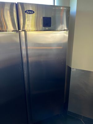 un réfrigérateur en acier inoxydable dans une cuisine, près d'une fenêtre