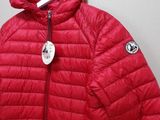 the red jacket is hanging on a hanger on the wall