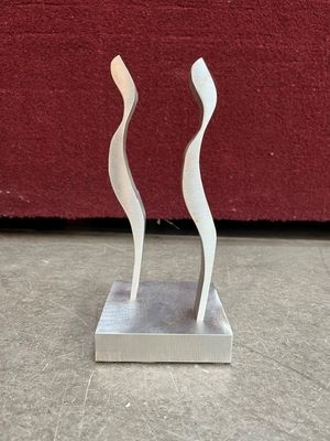 silver sculpture of two wavy shapes on a marble base on a red background