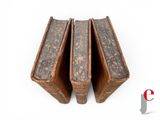 three old books stacked on top of each other on a white surface
