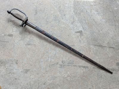 une vieille épée posée sur un sol en béton, avec une poignée en bois