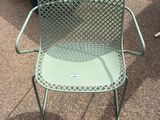 a green chair sitting on the ground next to a table and chairs