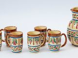 cinq tasses et un pichet posés les uns à côté des autres sur une table