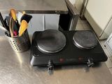 a stove top with two burners and utensils on it