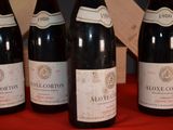 four bottles of wine are lined up on a red table
