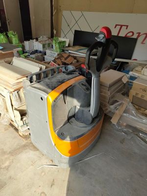 un chariot élévateur qui se trouve au milieu d'une pile de cartons