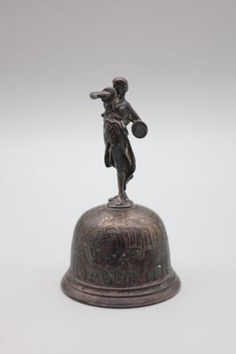 une cloche ancienne en bronze surmontée d'une statue représentant une femme tenant un panier