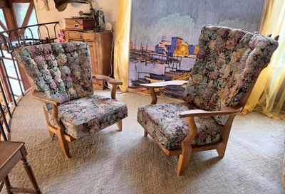 two chairs in a living room with a painting on the wall behind them