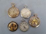 quatre montres de poche différentes posées sur une table