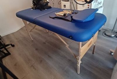 une table de massage bleue recouverte d'une housse bleue, dans une pièce