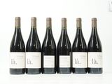 six bouteilles de vin sont alignées sur une surface blanche