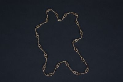 a silver chain with a bear on it sitting on a black surface