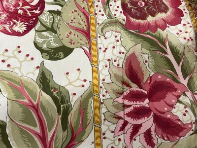 a close up of a bed with a red and green floral comforter