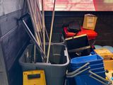 several buckets and brooms are lined up in the corner of a room