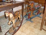 deux chevaux à bascule en bois posés par terre à côté d'une table