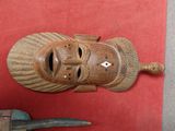 une image représentant un masque en bois et une paire de ciseaux sur un fond rouge