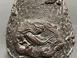 a silver vase with a dragon on it on a table