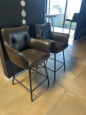 deux fauteuils en cuir noir placés l'un à côté de l'autre devant un mur noir