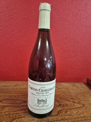 La bouteille de vin est posée sur la table, devant un mur rouge.