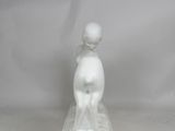 a white figurine of a boy on a platform