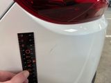someone is measuring the height of a white car with a ruler