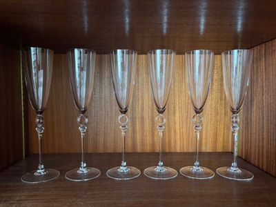 six empty wine glasses lined up on a shelf in a room