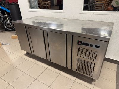 a stainless steel counter with three doors and a motorbike in the background