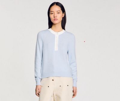 une photo d'une femme portant un pull bleu et un pantalon beige