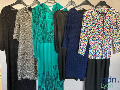 un ensemble de robes suspendues à un portant devant un mur