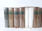 several books are lined up in a row on a white surface