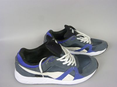 grey and blue sneakers with white soles on a grey surface