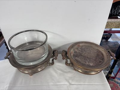 deux plats en argent posés sur une table, à côté d'un saladier en verre