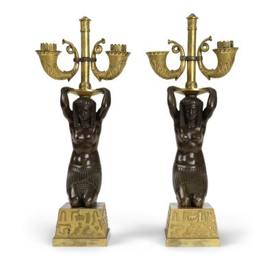 une paire de bougeoirs en bronze représentant des personnages tenant un candélabre