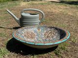 a bowl and a watering can sitting on the ground