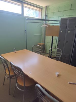 des tables et des chaises dans une pièce, avec des casiers en arrière-plan