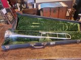 a silver trumpet in a green case on a wooden table