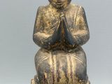 an image of a statue of a person sitting on top of a wooden block