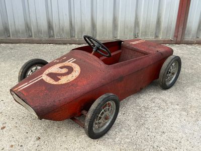 a red pedal car with a number on the front