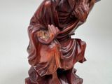 a wooden statue of a man sitting on a stool