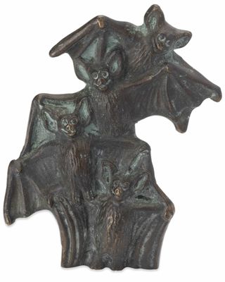 une statue représentant une chauve-souris, accrochée à un mur