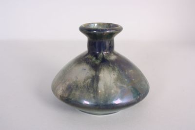 a small blue vase sitting on a white table