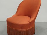 an orange chair with fringes on it in a room