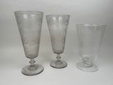 trois verres à pied et un verre à vin posés sur une surface blanche