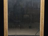 un miroir ancien dans un cadre doré sur fond noir, avec une chaise et une table en arrière-plan