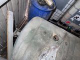 a dirty toilet in a dirty bathroom with a blue bucket