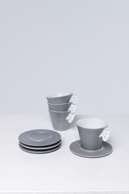 un service de trois tasses et soucoupes posé sur une table blanche