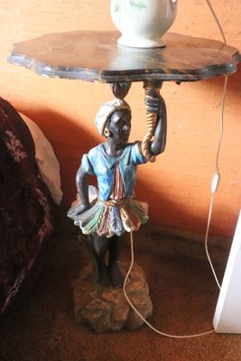 a statue of a man holding a tea pot on a table