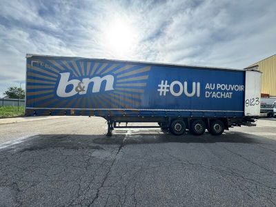 Le camion est garé sur le bord de la route, devant un immeuble.