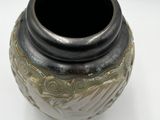 a black and gold vase sitting on a white surface