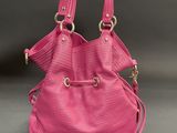 a pink purse sitting on top of a table next to a gray wall
